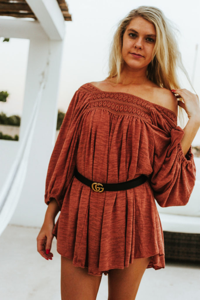 Blonde model touches her shoulder while wearing a trendy bohemian outfit